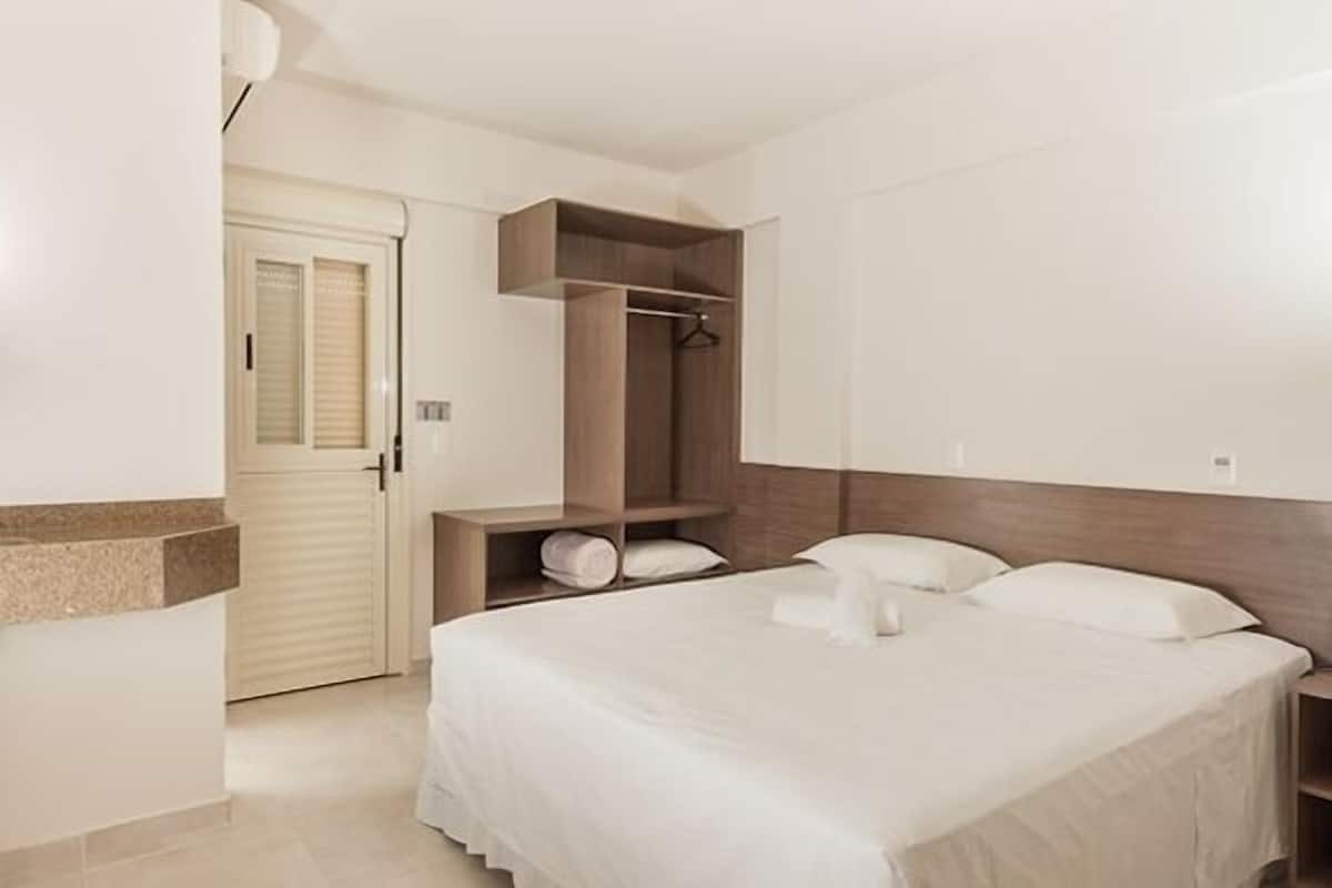 A hotel room with a bed, a wardrobe, and a bathroom.