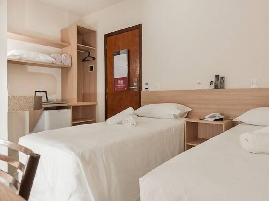 Habitación de hotel con dos camas, un escritorio, un armario y una puerta con un cartel.