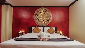 Una camera d'albergo con un letto grande, pareti rosse e un elemento decorativo circolare sopra il letto.