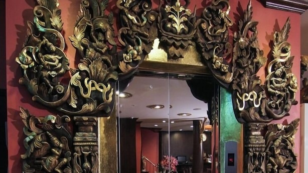 Ingresso di un hotel con elaborate decorazioni in legno intagliato e una porta in vetro.