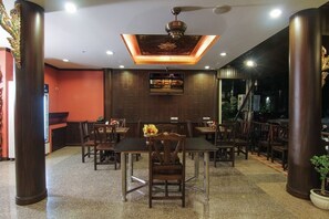 Un restaurante con varias mesas y sillas, un ventilador de techo y una pantalla de televisión en la pared.