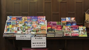 Esposizione di guide turistiche e mappe al banco informazioni, con indicazioni sui tour e sui trasporti per l'aeroporto.