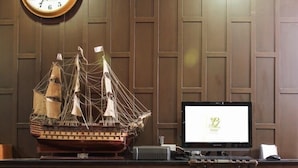 Una scrivania in legno con un modellino di nave, un portatile e una sedia.