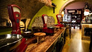 Un espace bar aménagé avec du matériel ancien, un mur en pierre et un plafond en briques.