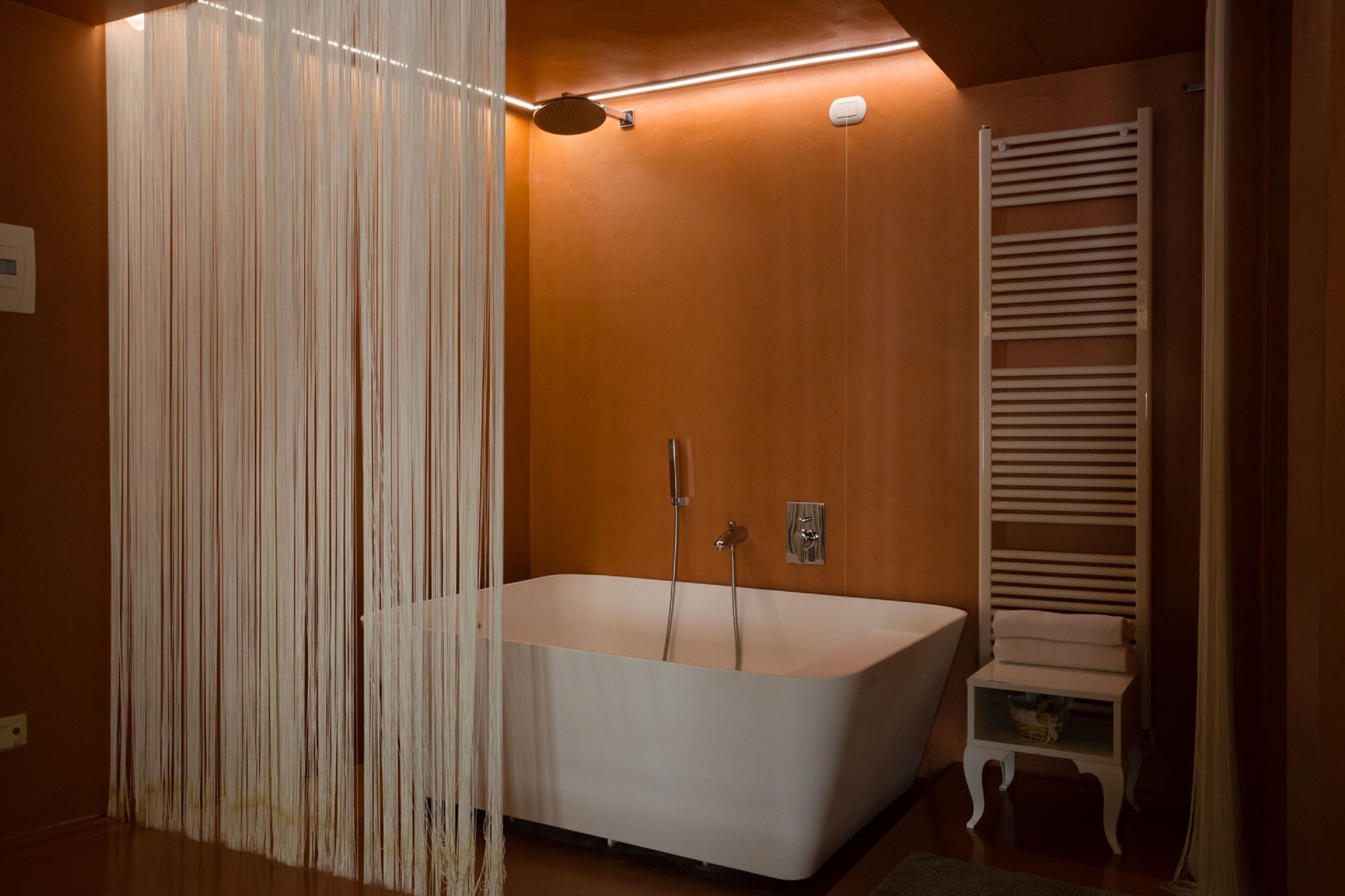 A modern bathroom with a freestanding bathtub, a towel rack, and a showerhead.