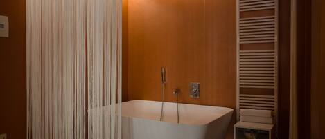 A modern bathroom with a freestanding bathtub, a towel rack, and a showerhead.
