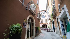 Une rue étroite où se trouvent un hôtel appelé « HÔTEL ALESSI » et un restaurant appelé « RESTAURANT ALESSI MILITARE ».