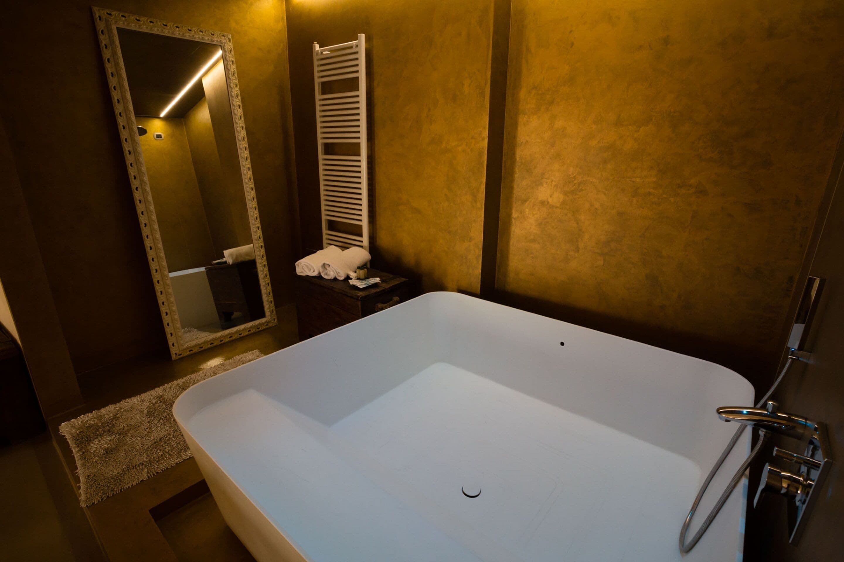 Une salle de bain moderne avec une grande baignoire, un miroir et un porte-serviettes.