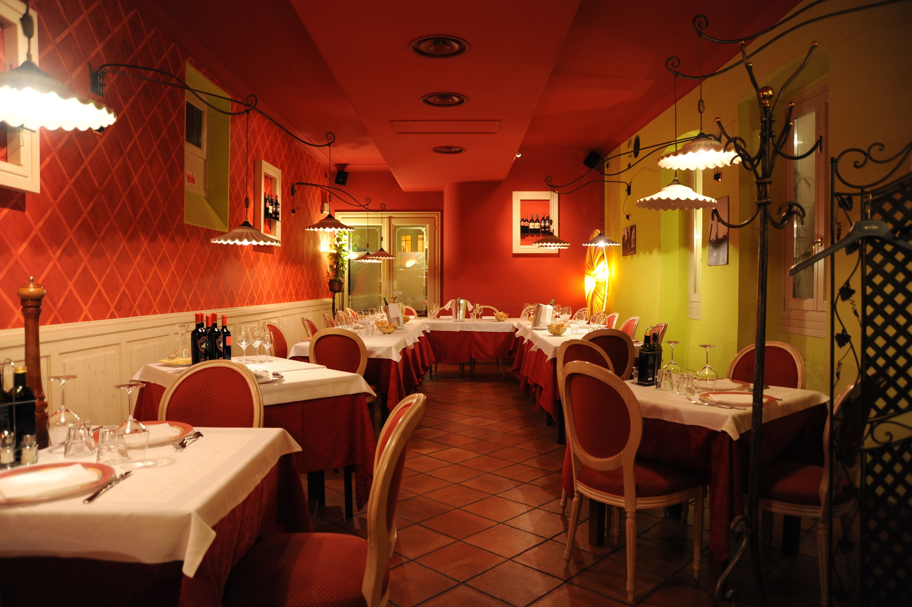 A restaurant with multiple tables set for dining, featuring a red and yellow color scheme and traditional decor.