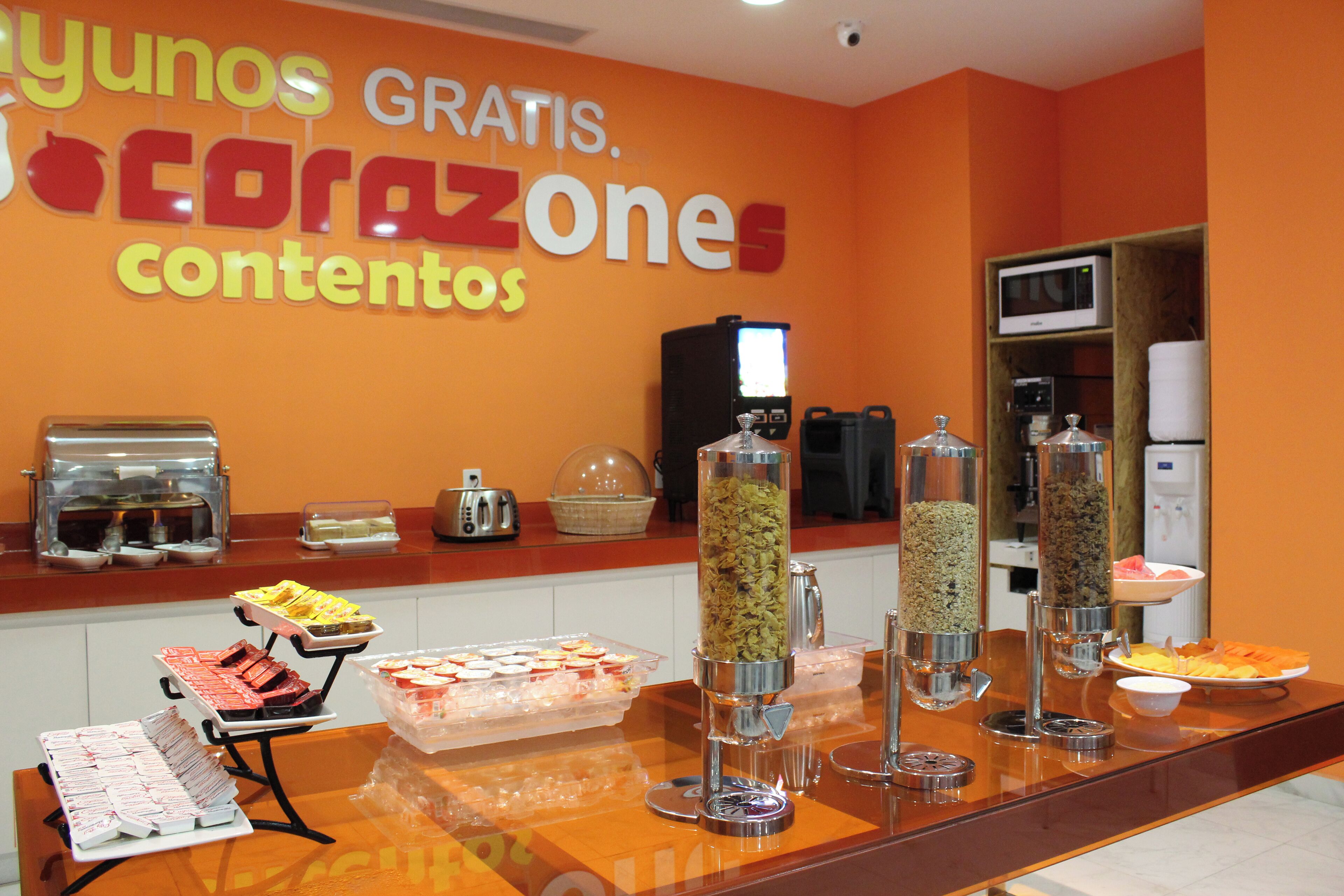 Zona de bufé con diversas opciones de comida y un cartel anunciando desayuno gratuito.