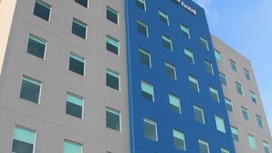 A modern hotel building with a prominent 'one' sign, multiple windows, and a clear sky. - One Guadalajara Tapatio (Tlaquepaque)