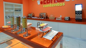 A breakfast buffet area with various food dispensers, a coffee machine, and a toaster. - One Guadalajara Tapatio (Tlaquepaque)