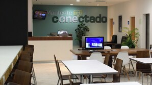 A modern conference room with a reception desk, a flat-screen monitor, and a large plant. - One Guadalajara Tapatio (Tlaquepaque)