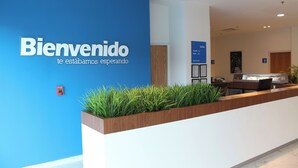 A reception desk with a blue wall and a welcome sign. - One Guadalajara Tapatio (Tlaquepaque)
