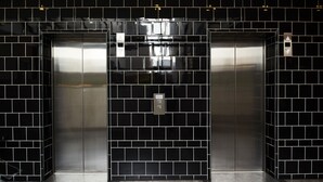 Un ascensore moderno con pareti in piastrelle nere e finiture metalliche.
