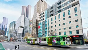 Un edificio moderno con un tram verde e bianco di fronte.