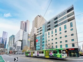 Un edificio moderno con un tranvía verde y blanco en primer plano.