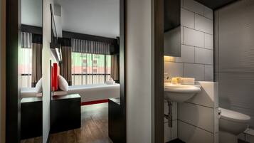 Une chambre d’hôtel moderne dotée d’une grande fenêtre, d’une banquette intégrée, d’un lavabo et de toilettes.