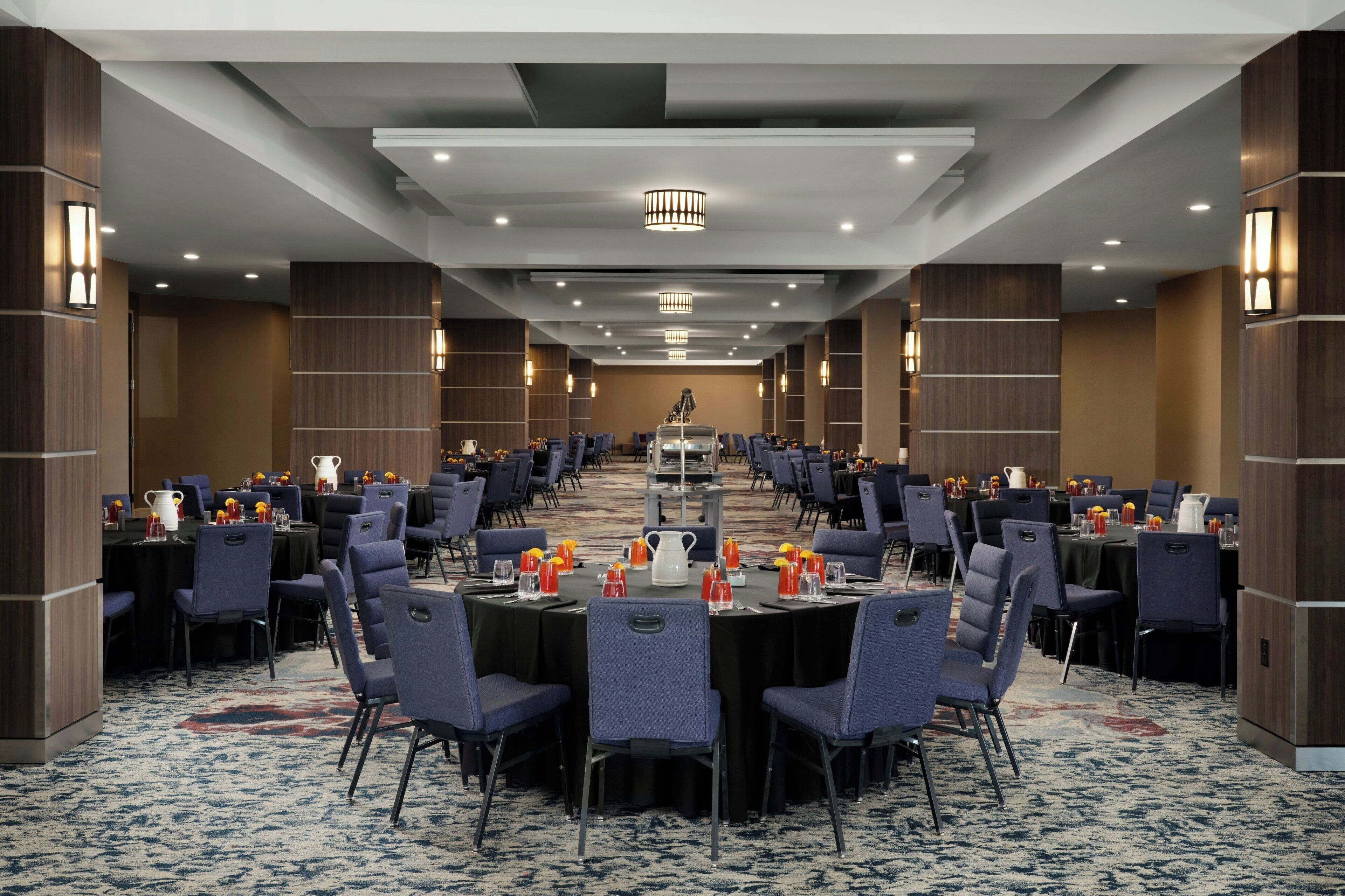 A large conference room with round tables, chairs, and a long table in the center.
