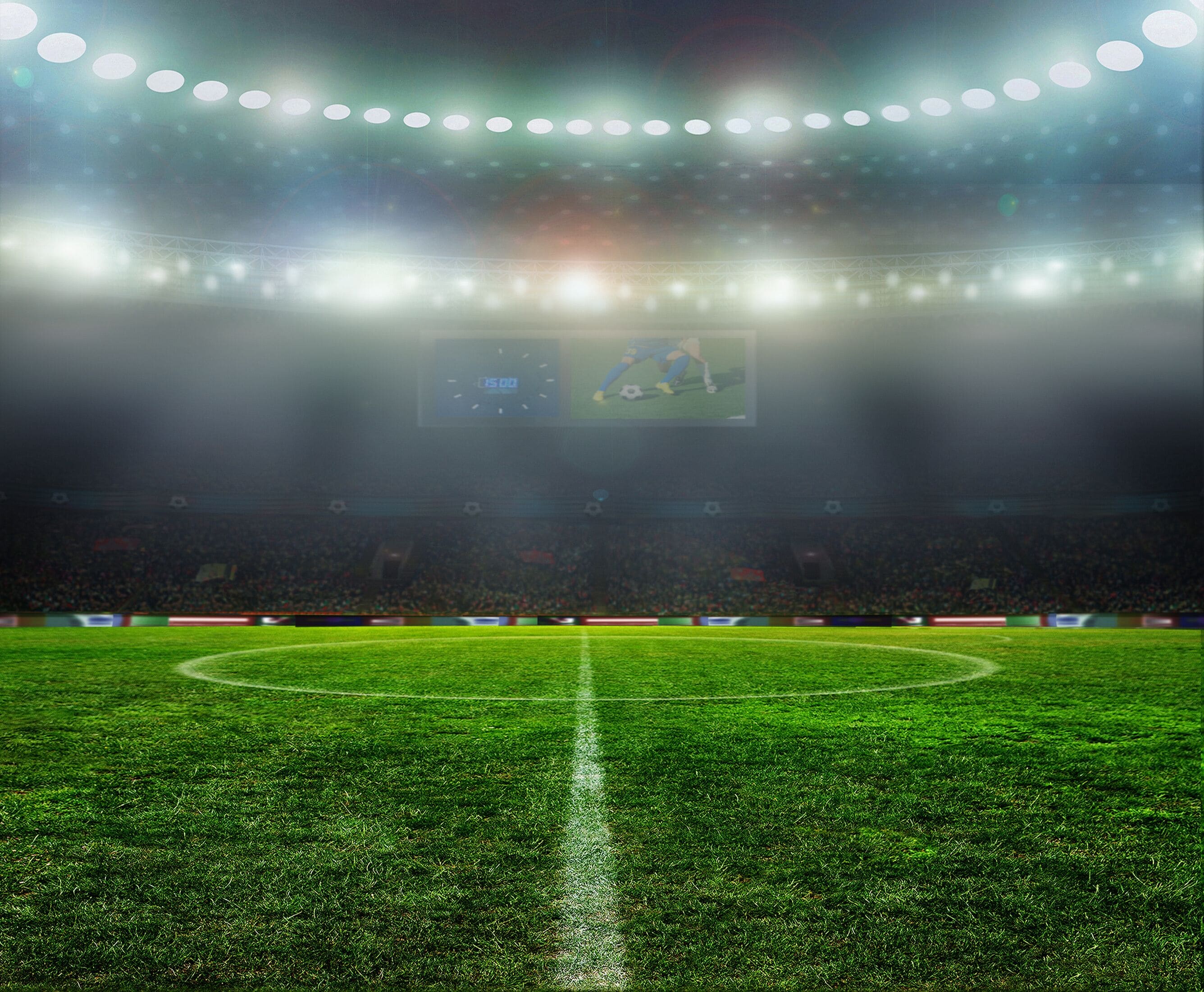 A stadium with a green field and floodlights.