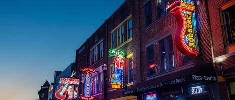 A street lined with brightly lit buildings, including a record shop and a bar.