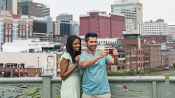 Una pareja tomándose un selfie en un balcón con un horizonte urbano de fondo.
