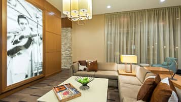 A modern living room with a large digital art display, a sofa, a coffee table with books and apples, and a lamp.