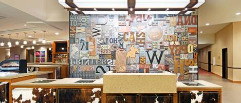 A reception area with a modern design, featuring a wall with various letters and symbols, a counter with a cowhide design, and a display case.