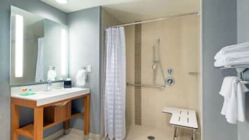 A modern bathroom with a wooden vanity, a glass shower enclosure, and a white towel rack.