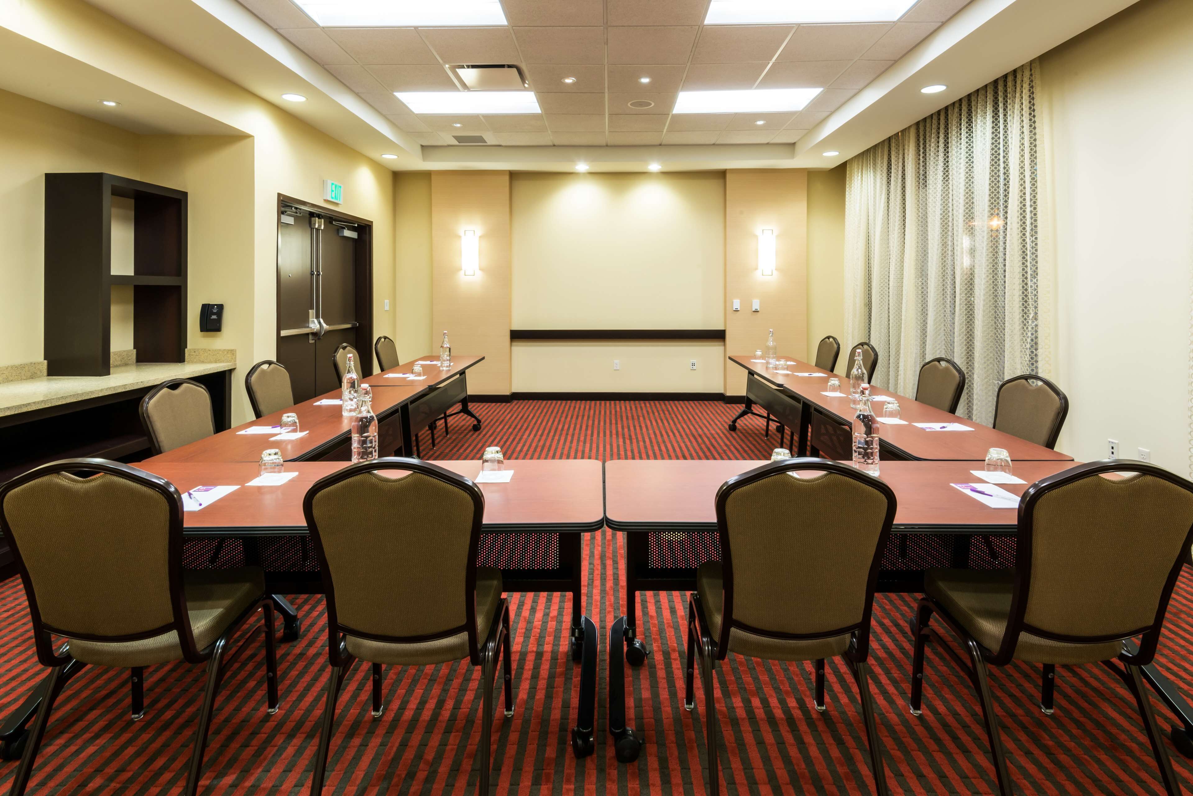 A conference room with a long table, chairs, and a projector screen.