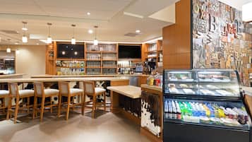 A bar area with wooden chairs, a counter with bottles, and a refrigerated display of drinks.