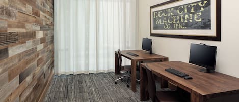 Una sala de conferencias con dos escritorios, cada uno con un ordenador y teclado. La sala tiene paneles de madera en la pared y un cuadro enmarcado.