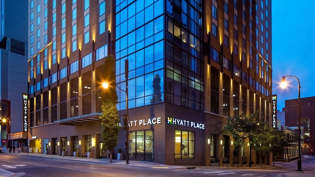 Een modern hotel met een glazen gevel, verlichte reclameborden en een schoon stadsgezicht.