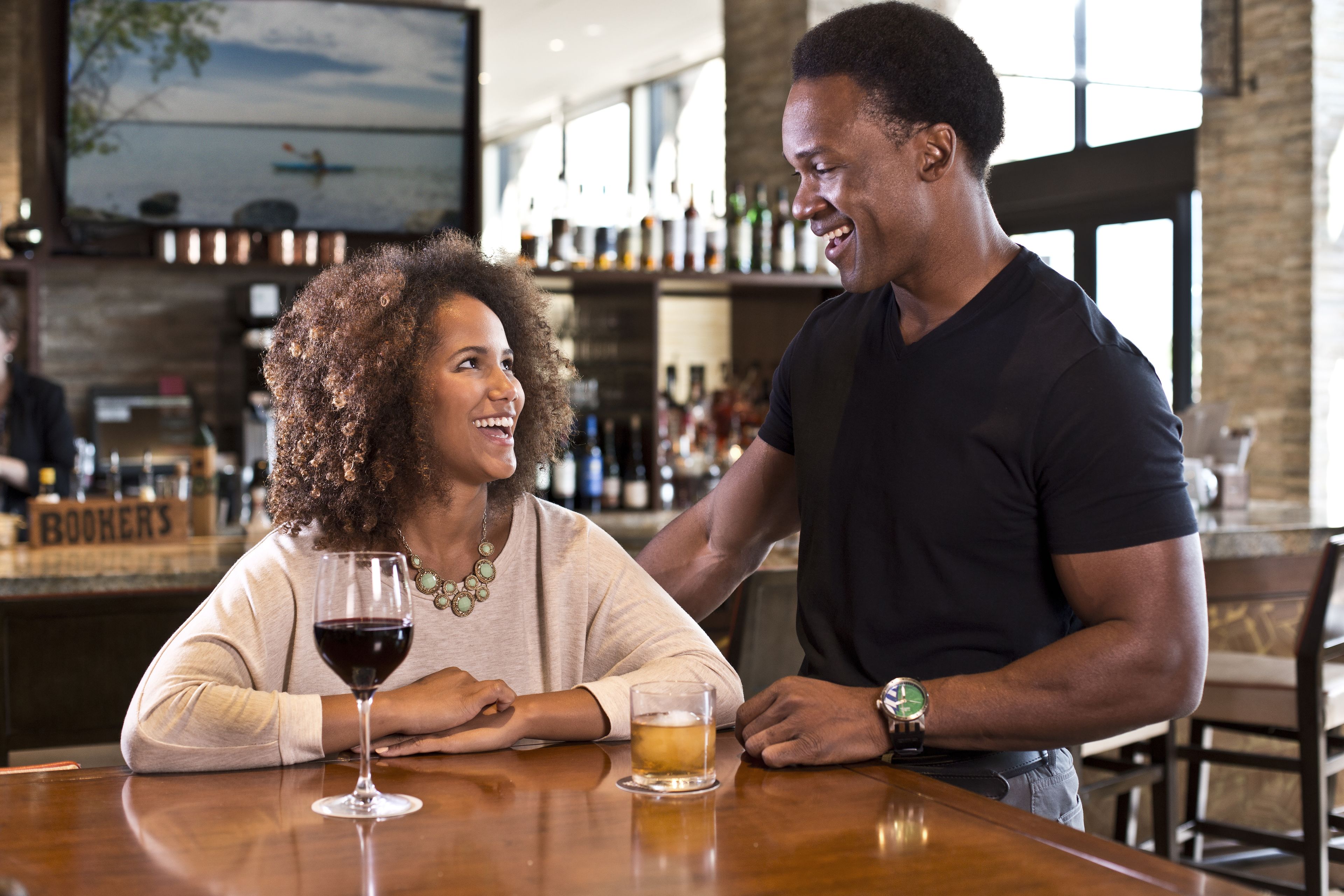 A couple seated at a bar with a view of the sea through large windows.