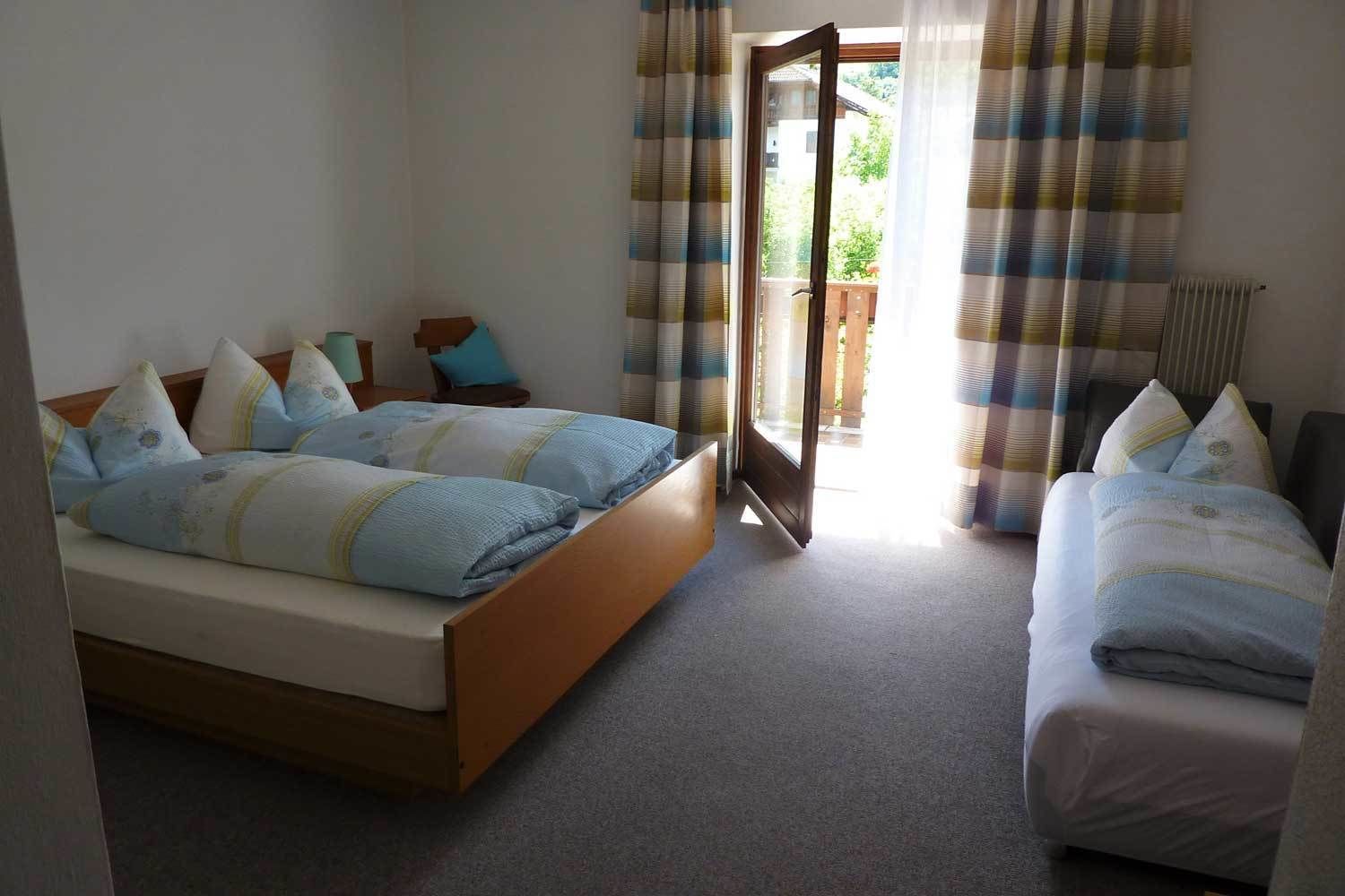 Un dormitorio con una cama grande, una cama más pequeña y una ventana con cortinas.