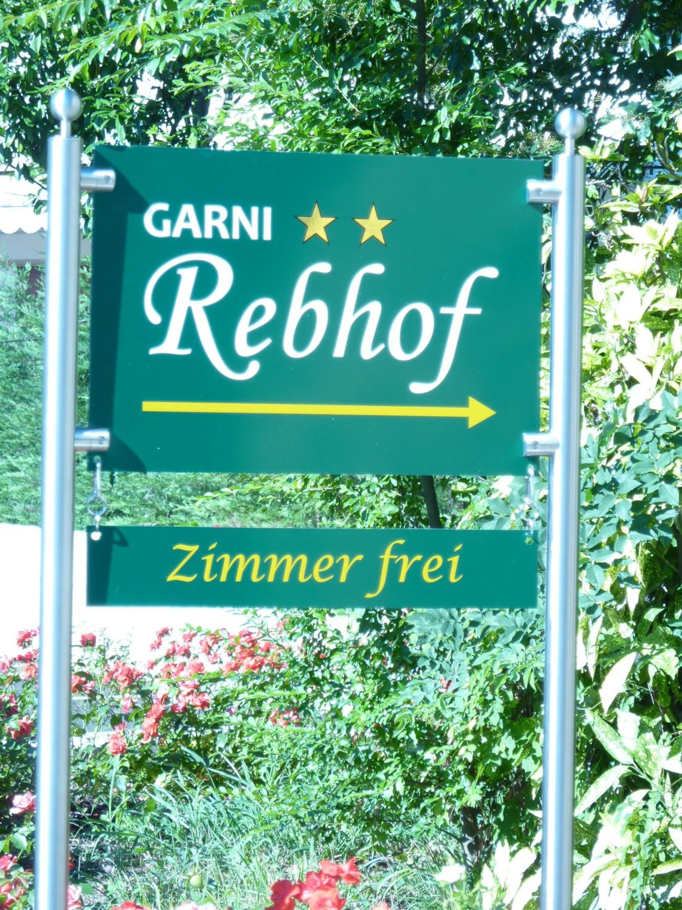 A sign for GARNI Rebhof with an arrow pointing right, indicating the direction to the hotel.