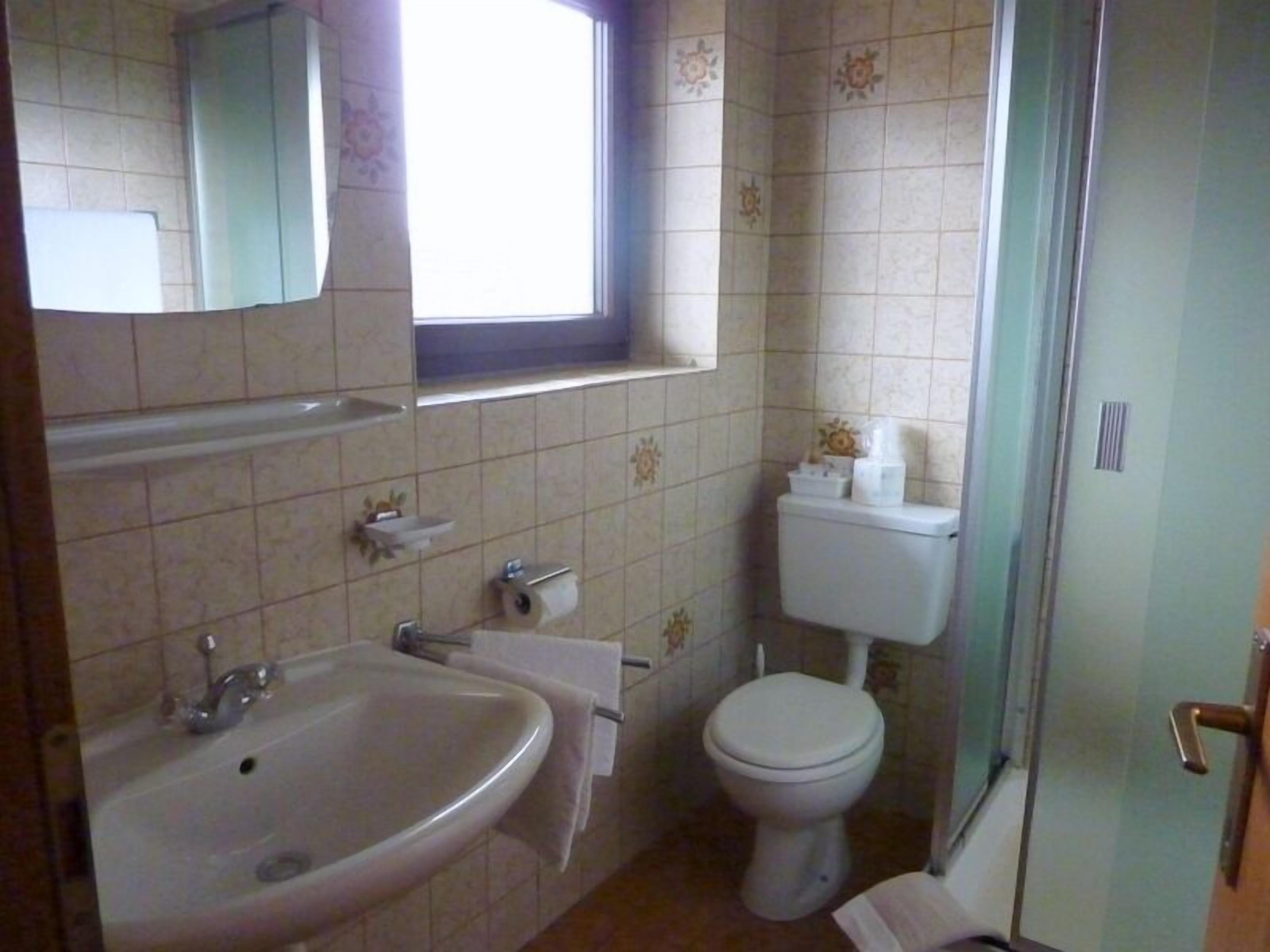 Un baño con lavamanos, inodoro y ventana.
