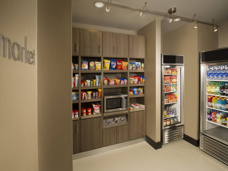 Una kitchenette con microondas, estantes llenos de aperitivos y un refrigerador con bebidas.