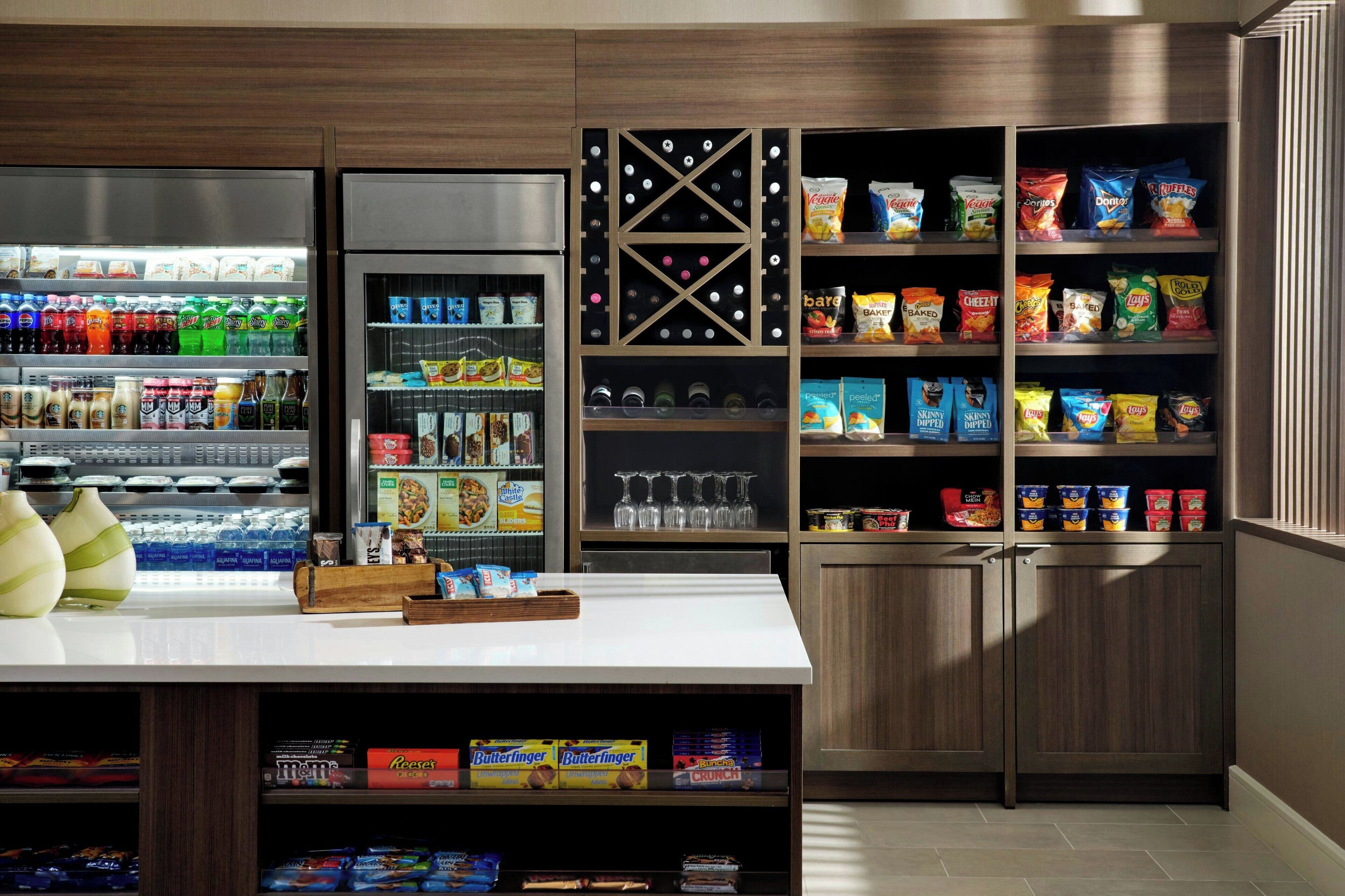 Een overzichtelijk gedeelte met snacks en drankjes, diverse producten en een wijnrek.