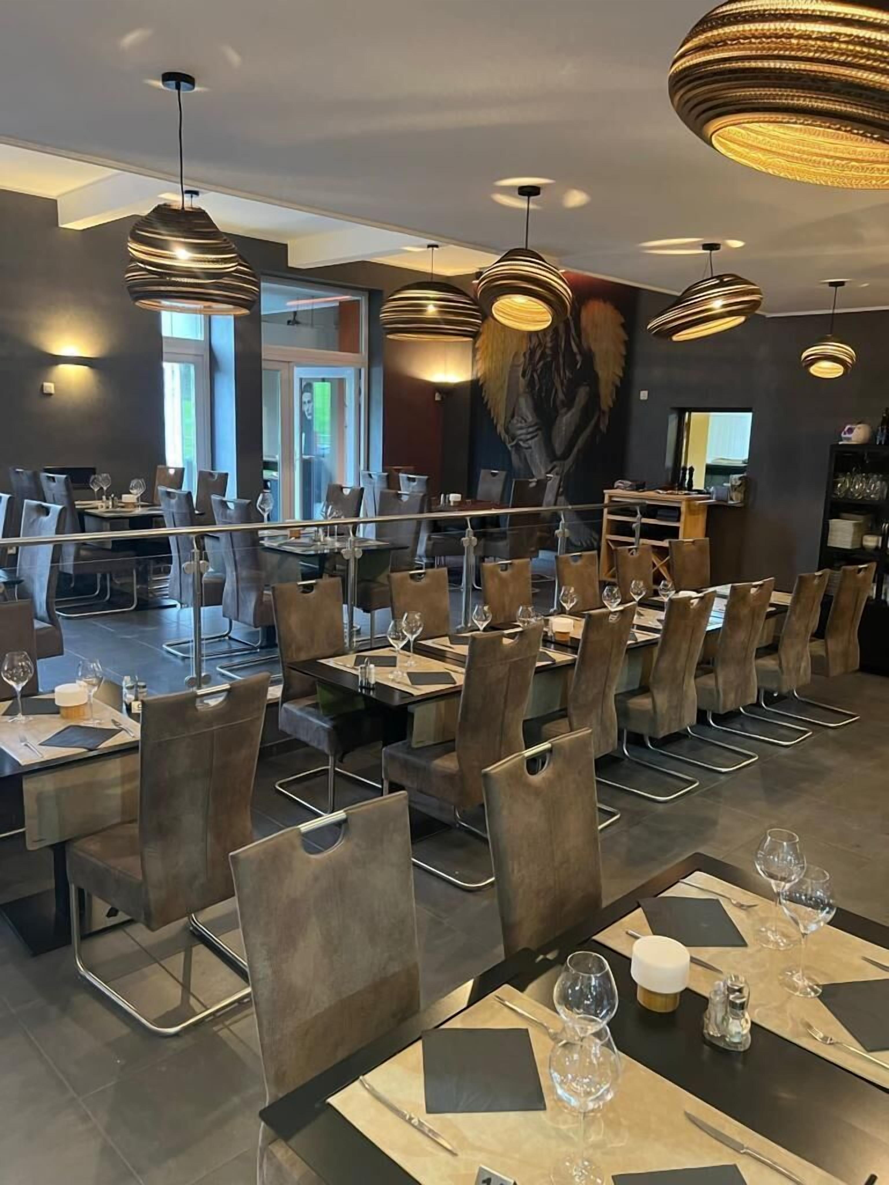 A modern restaurant interior with high tables, chairs, and pendant lighting.