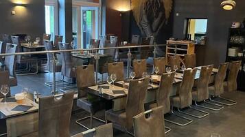 Un interior de restaurante moderno con mesas altas, sillas e iluminación colgante.