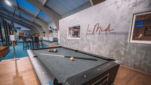 Un tavolo da biliardo con le palle, un'area bar e un muro con un cartello che riporta la scritta "L.Midi".