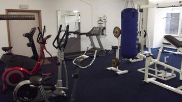 Een sportschool met hometrainers, loopband, krachttoestellen en een bokszak.
