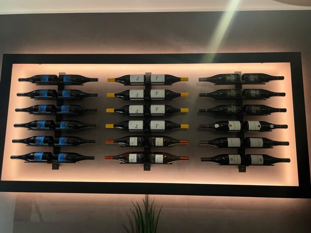 Un présentoir mural où sont exposées des bouteilles de vin, disposées en rangées.