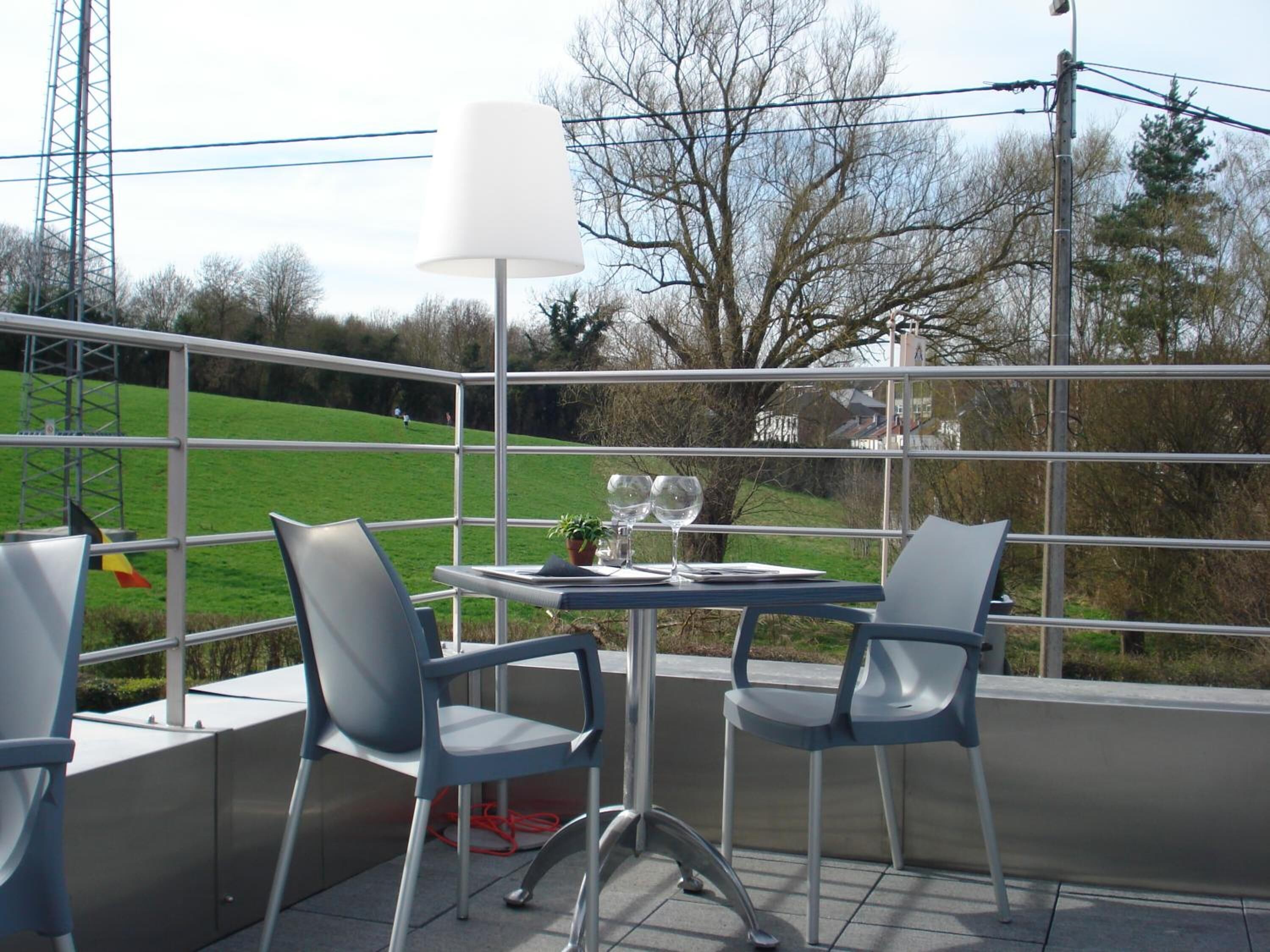 Un balcon avec deux chaises, une table et une lampe.