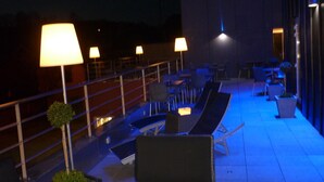 Una terrazza sul tetto con posti a sedere all'aperto, tavoli e lampade.