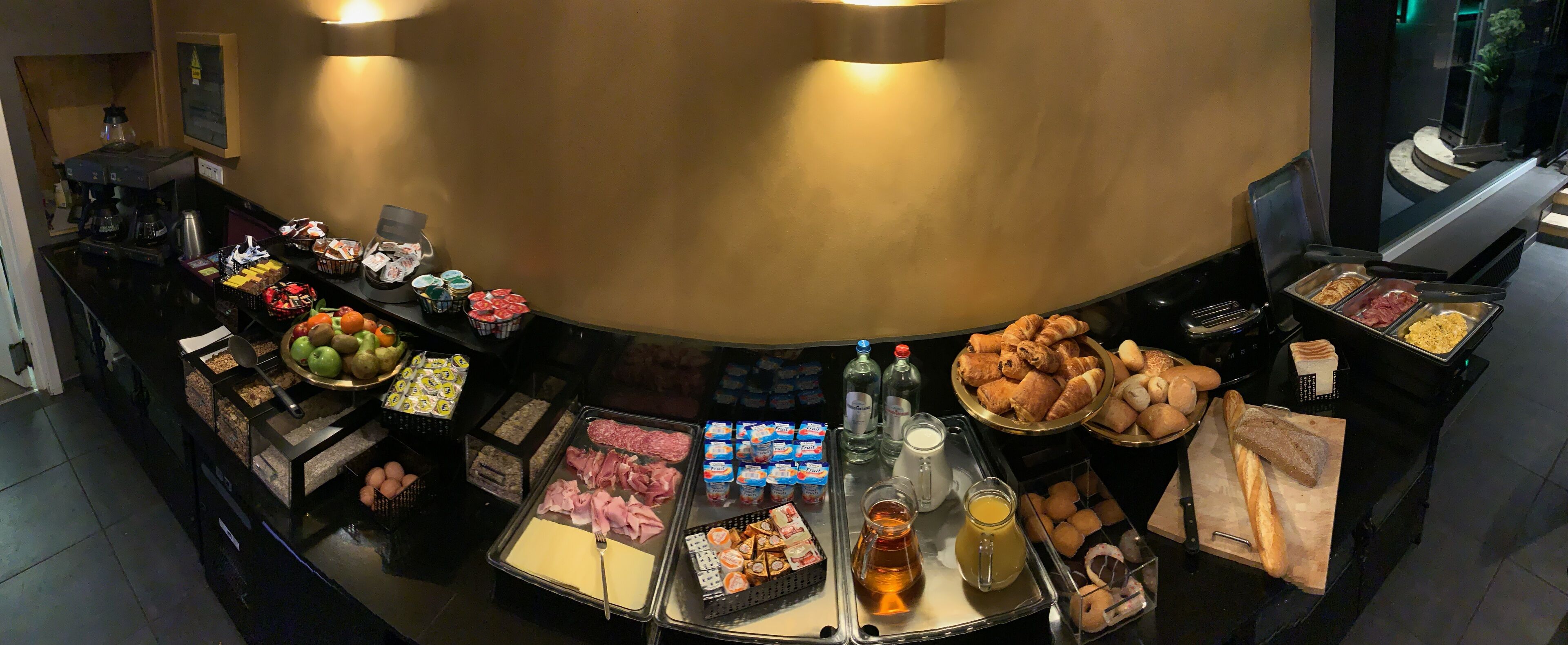 A buffet with various food items including meats, cheeses, fruits, and pastries.