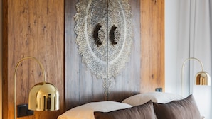 A bedroom with a wooden headboard, a decorative wall piece, a bed with white and brown bedding, and two bedside lamps. - Quinta da Abelheira (Ponta Delgada)