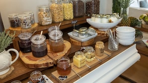 A breakfast buffet with various jars of spreads and condiments, including honey, lemon curd, and peanut butter. - Quinta da Abelheira (Ponta Delgada)