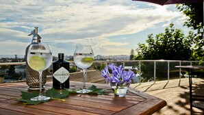 A wooden table with a bottle of Hendrick's gin, two glasses of a clear beverage, and a small vase with purple flowers. - Quinta da Abelheira (Ponta Delgada)